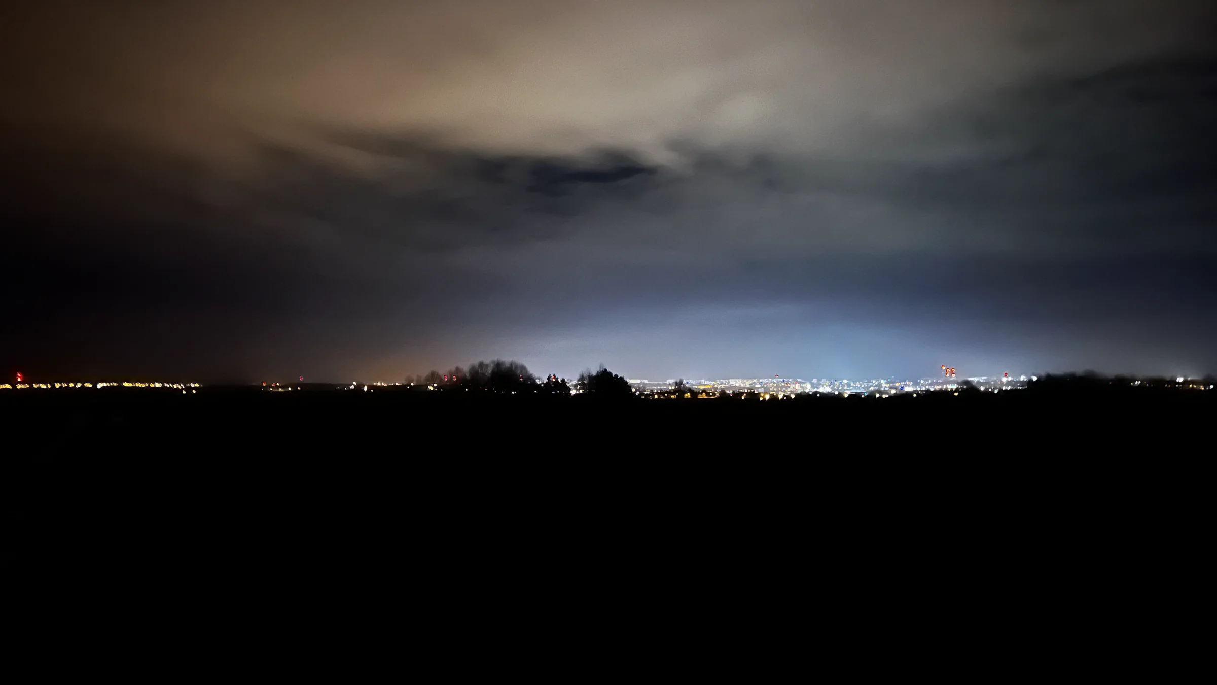 Chmury na nocnym niebie nad światłami miasta.