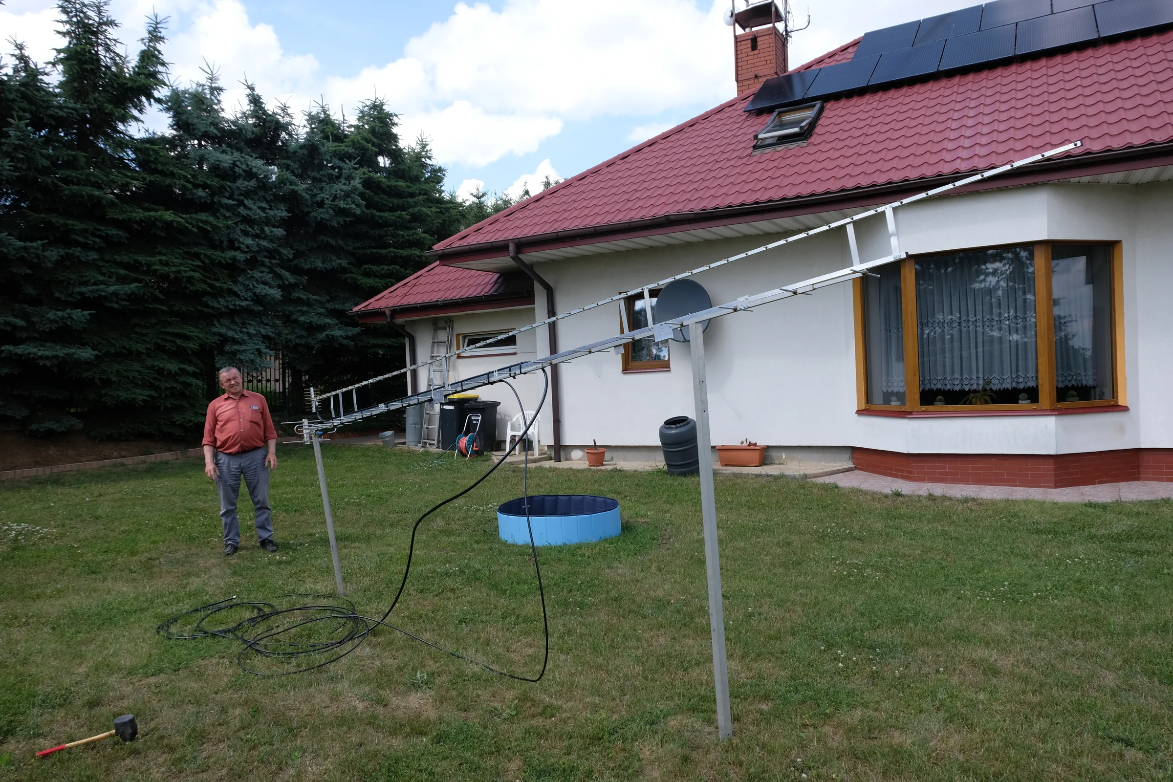 Długa antena Yagi przed domem; w tle stoi Ryszard Więcaszek.